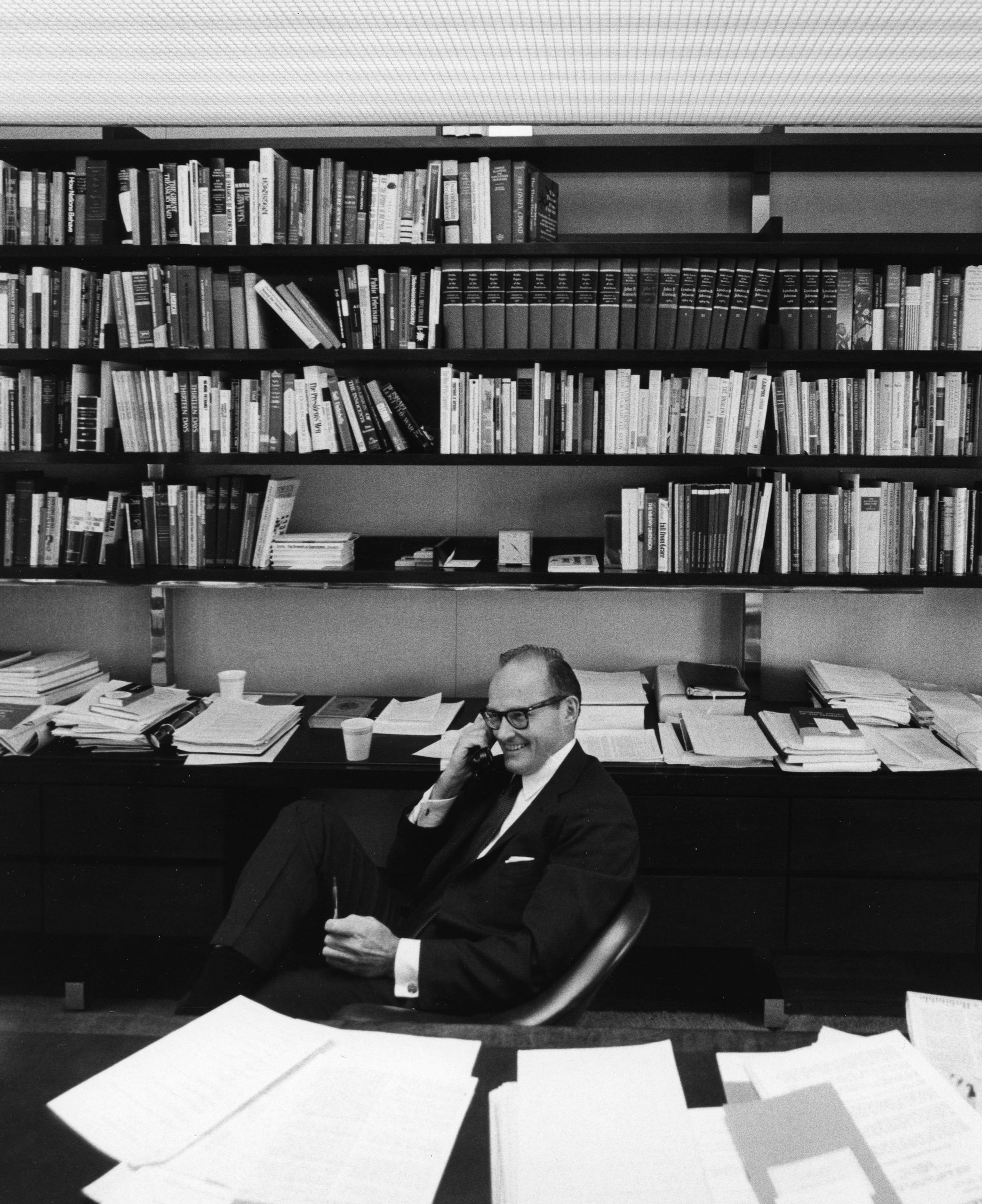 McGeorge Bundy, a white man, is dressed in a suit and sits with books behind him. He holds a telephone receiver and looks busy. Bundy was the Ford Foundation president that promoted a major shift to civil rights funding.