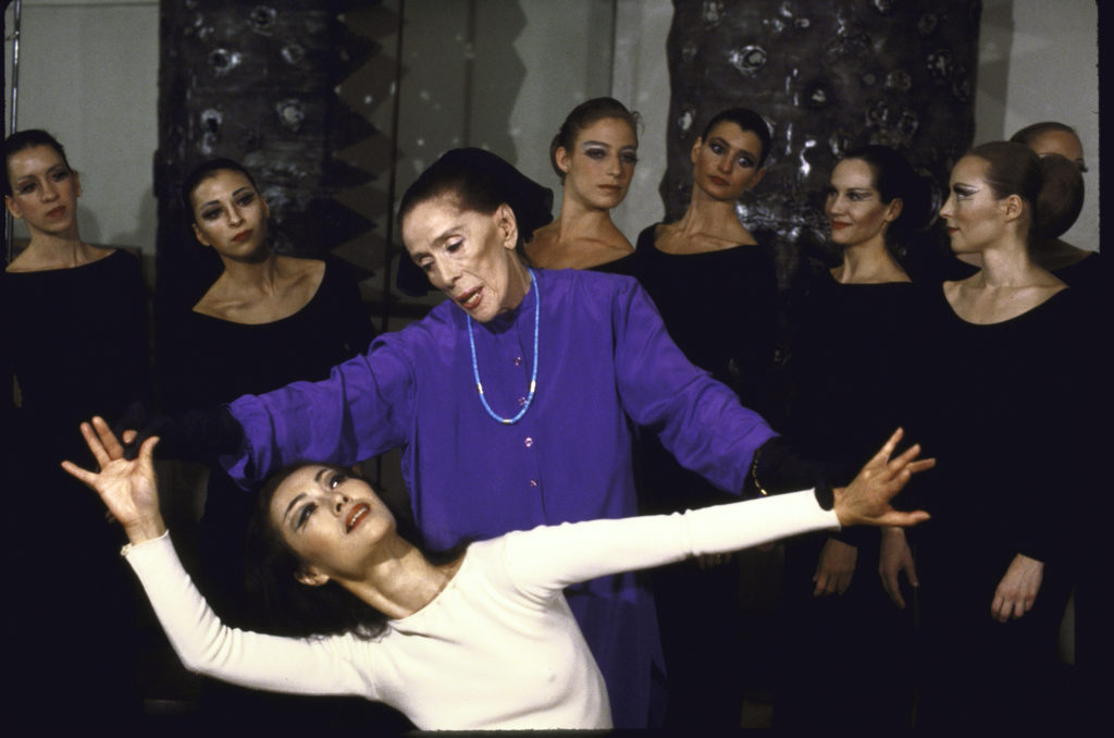 A photograph of choreographer Martha Graham in action, rehearsing with dancers as they work on her piece, "Heretic."