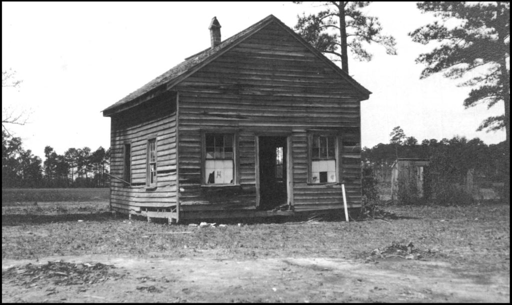 A run-down wooden school building in North Carolina, with windows and parts of the siding are missing. This photograph shows the dire condition of African American schools in the US South in the early twentieth century.