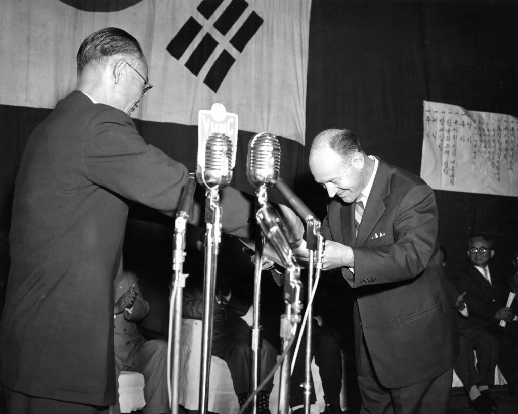 Marous W. Scherbacher, Cultural Attache, American Embassy, Seoul, is pictured receiving from Dr. Choi Kyu-nam, Minister of Education, a commendation for the Rockefeller Foundation whose financial Assistance made possible the publication of the first Korean (Hangul) Dictionary. The citation was made on Hangul Day, a national holiday, October 9, 1957.