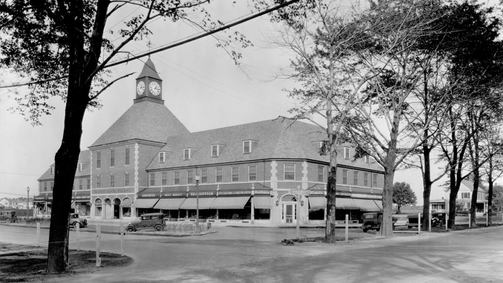 Black and white photo of the Radburn commercial center. Entrance to the commercial center is lined with trees.