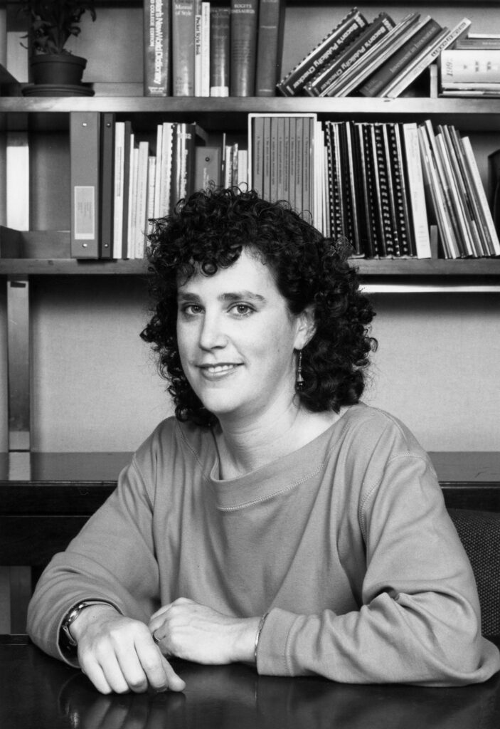 black and white portrait of Margaret Hempel, seated in front of bookshelves, circa 1990